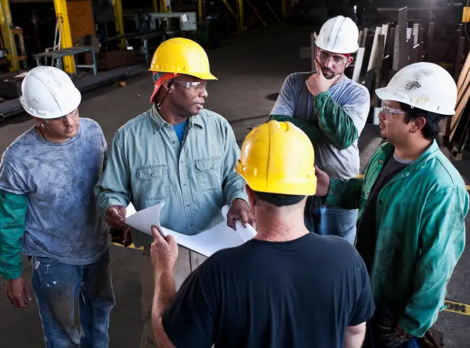 group of people in hard hats in discussion with safety gear on