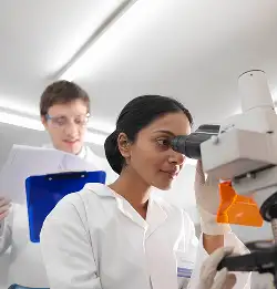 chemist looking through microscope