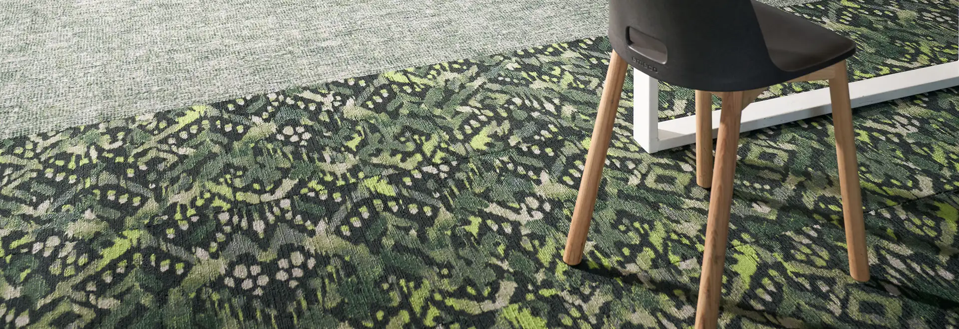 close up of textural geometric green carpet tile butting up to gray carpet tile