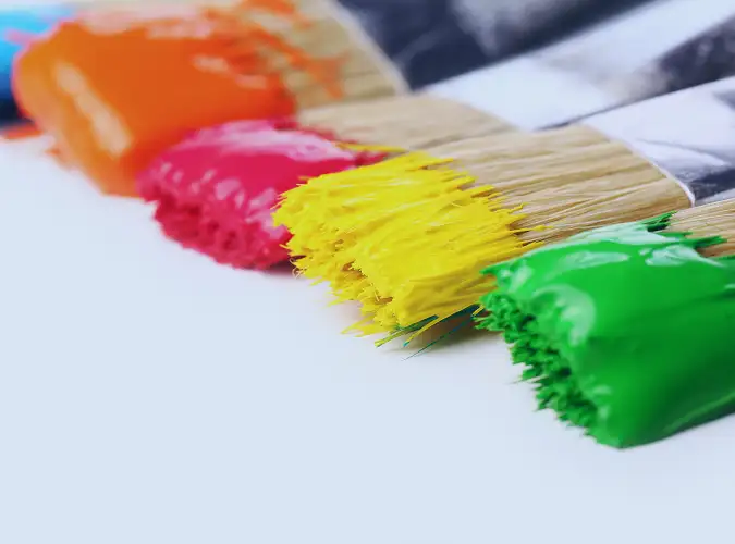 several paint brushed with colorful paint on each