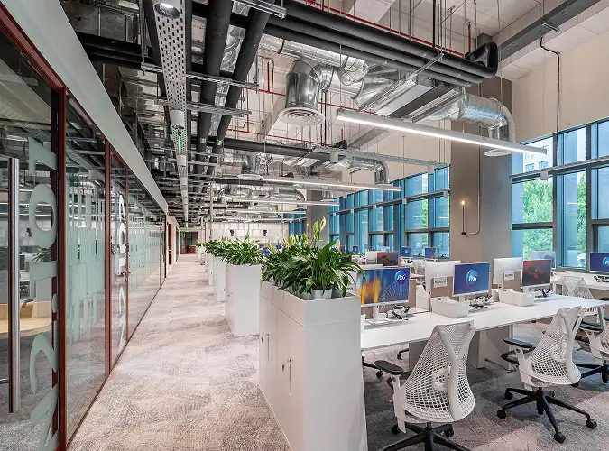 open office with eposed duct work, plants and carpet tile flooring 