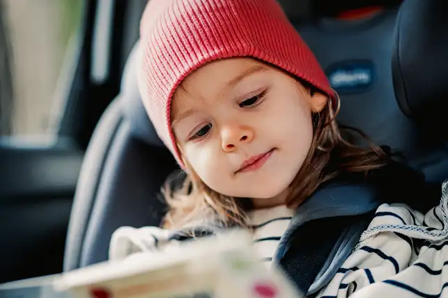 child in a car seat with red hat