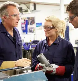 group of three people in blue cover alls wearing safety glasses