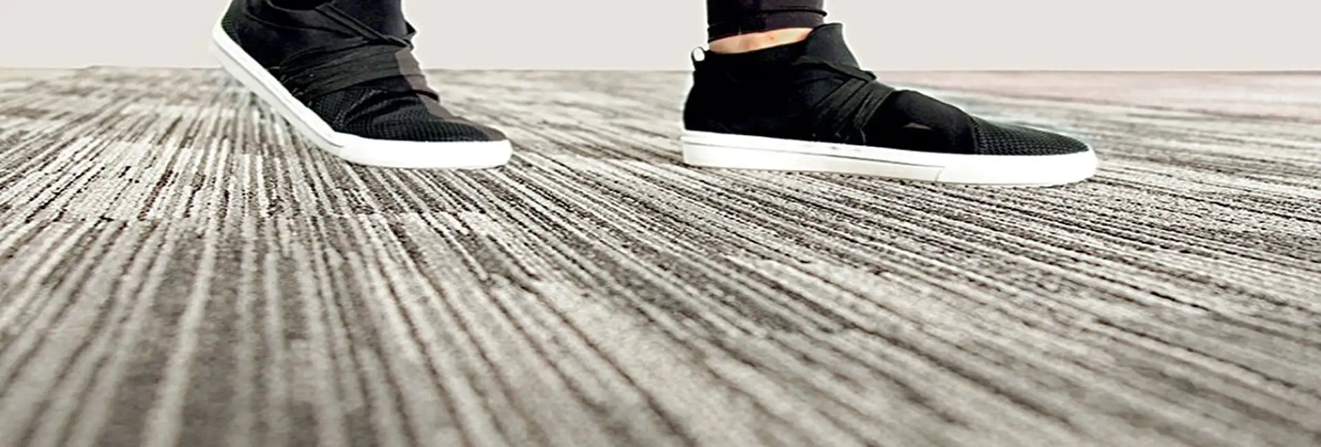 close up of black shoes with white soles on textured carpet tiles